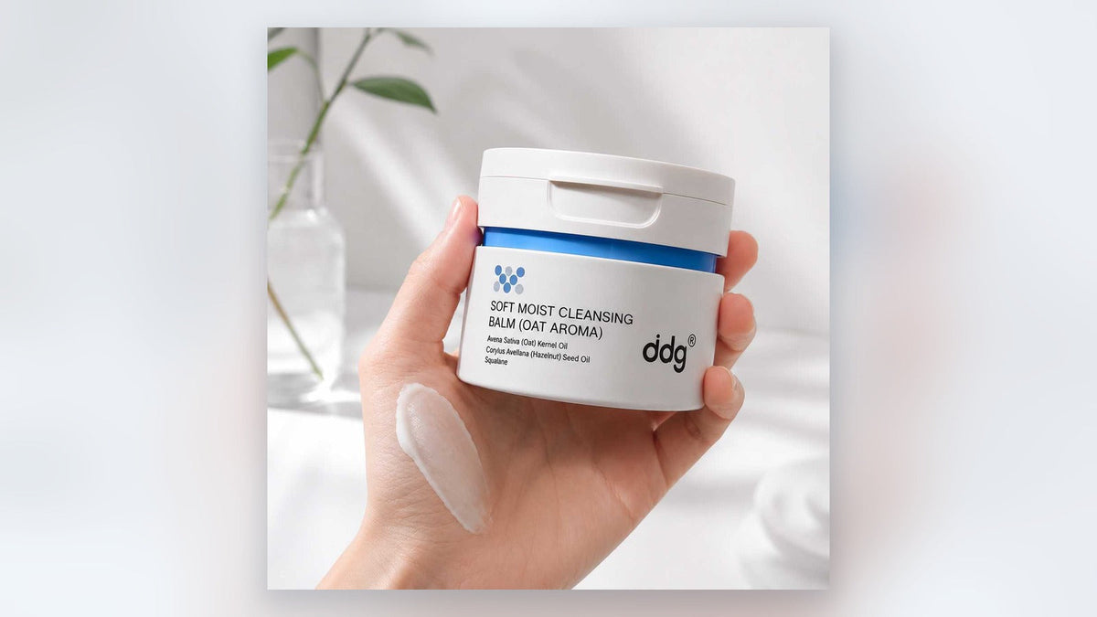 Hand holding ddg oat cleansing balm in soft natural light