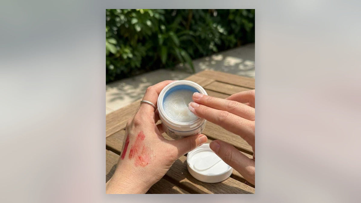 Hands using ddg cleansing balm on makeup swatches outdoors